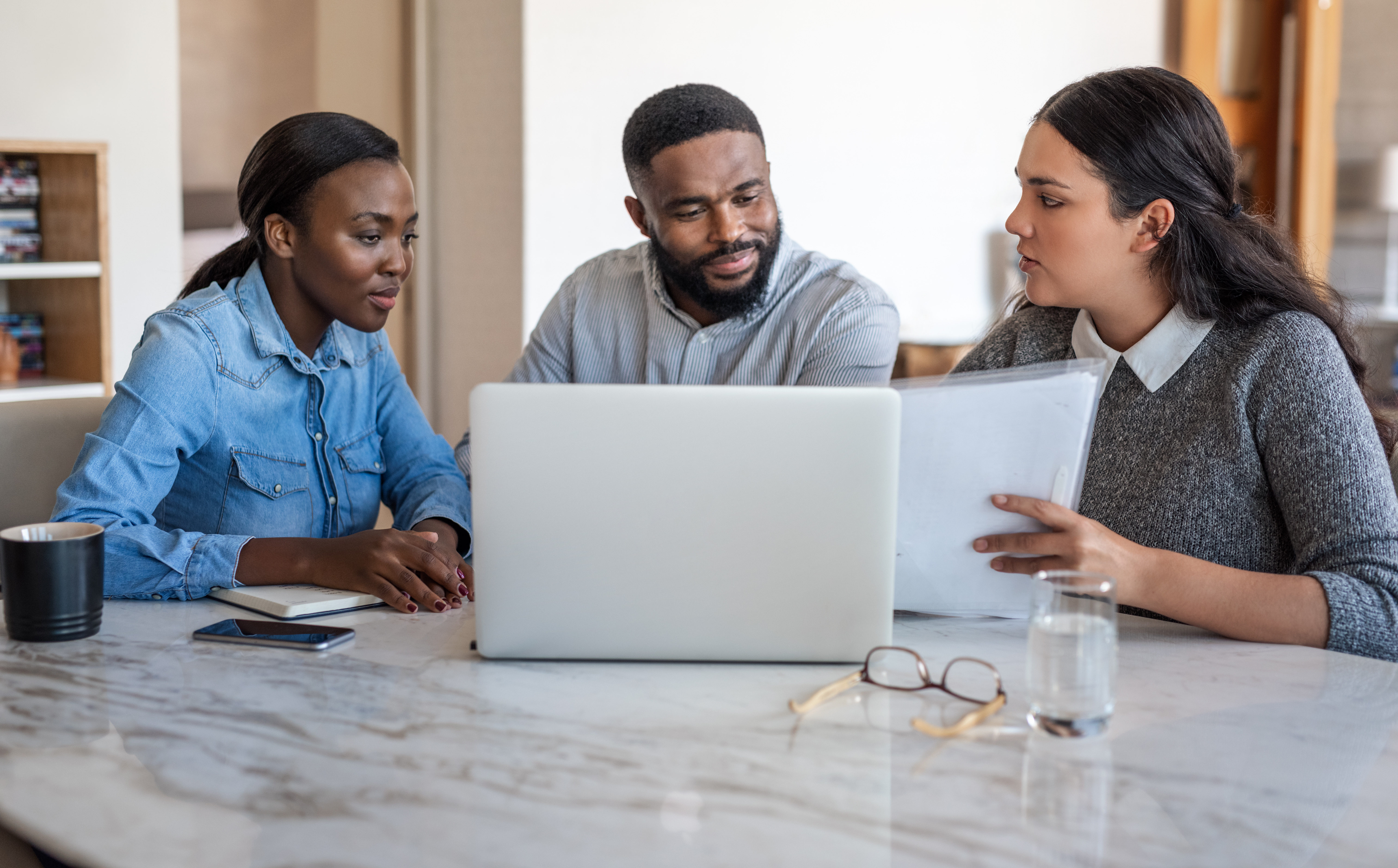 Couple sitting at desk with a financial planner looking at computer and documents.