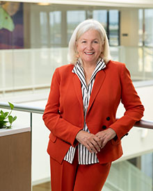 Woman wearing red suit smiling at camera and leaning on railing.