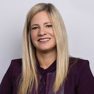 Head shot of Janelle Woods, a white woman with long, straight blonde hair, smiling and wearing a maroon-colored blouse.