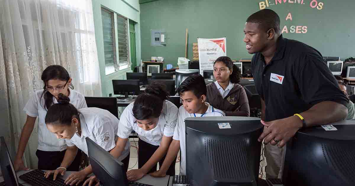 Kelvin Beachum, dressed in a polo shirt, talks with students in a computer lab in Mexia, Texas.