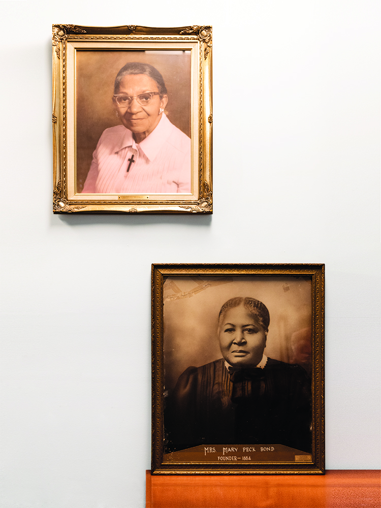 A large portrait of Eva P. Mitchell (top) is displayed in the lobby of the apartment building in Lemington that bears her name. Her son, the late former Pittsburgh Police Commander Herman Mitchell, who was well-known in the Pittsburgh community, was a Lemington Home board member who helped raise money for the residence and named it after his mother. The portrait of Mary Peck Bond once hung at the now-closed Lemington Home for the Aged. It is currently stored in the Lemington Home Corps. archives, which are held by Lemington Residential Corp. Board Member Joy Starzl. (Photo credit: Kitoko Chargois).