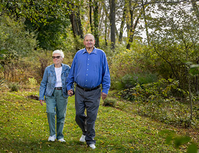 Man and woman walking in wooded area.