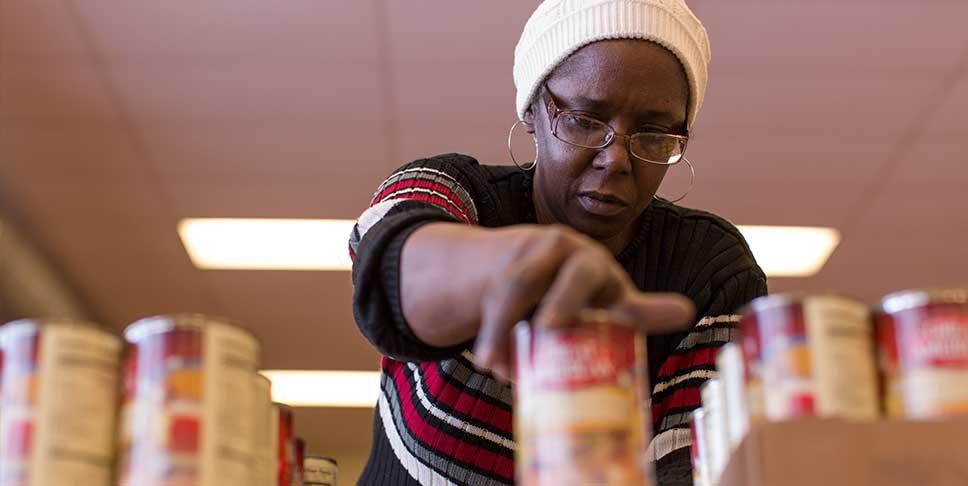 Once a month, the Hazelwood Food pantry opens for residents to pick groceries and other household items. Volunteer L'Tanya Jackson lines up canned soup and vegetables for clients.