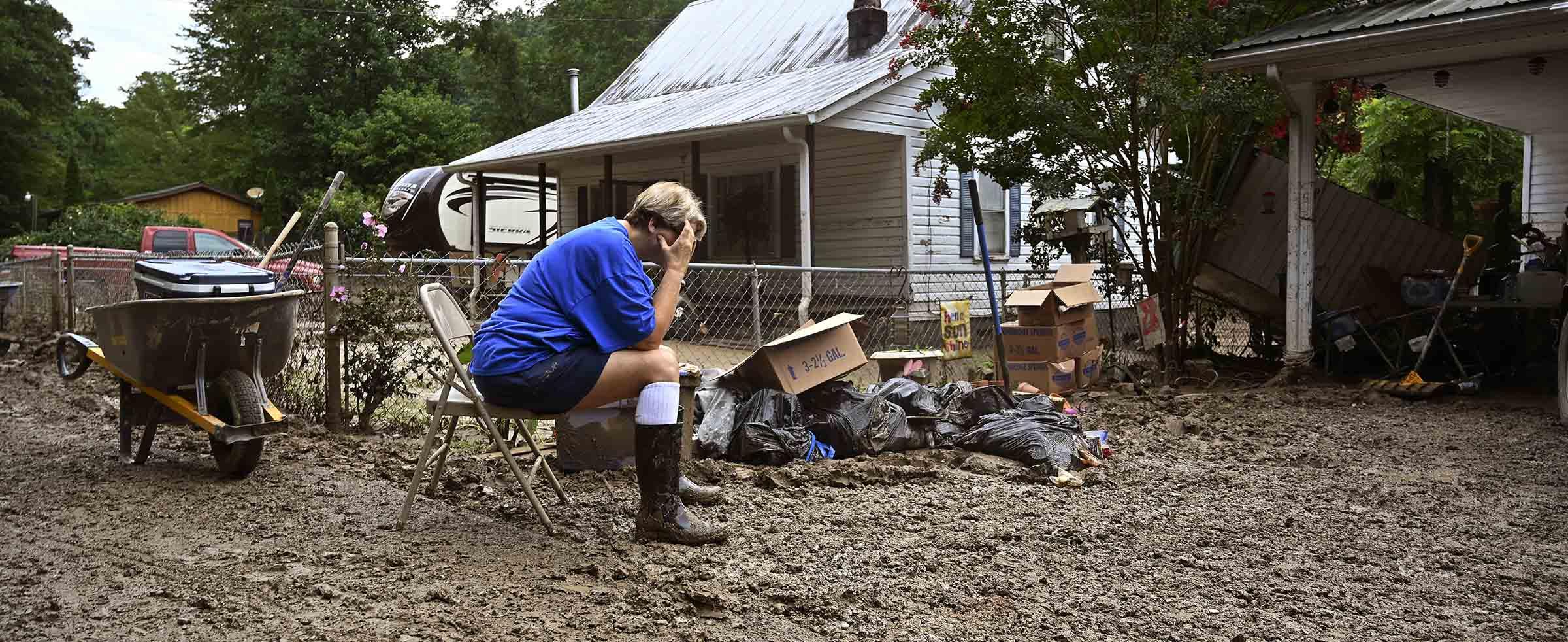 Teresa Reynolds sits exhausted as members of her community clean the debris from their flooded homes in Ogden Hollar in Hindman, Ky., Saturday, July 30, 2022, after record rains struck the area. (AP Photo by Timothy D. Easley)