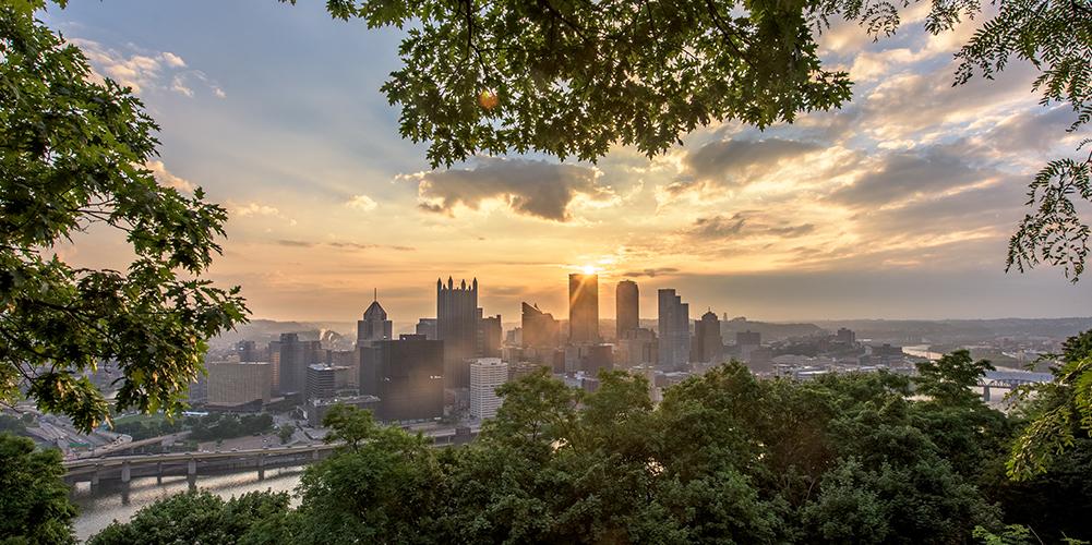 Trees on Mt. Washington frame the Pittsburgh skyline during a beautiful sunrise. Photo by Dave DiCello.